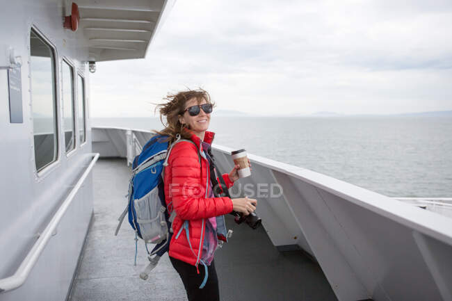 Portrait of woman on ferry to Vancouver Island, holding coffee cup and camera — Stock Photo