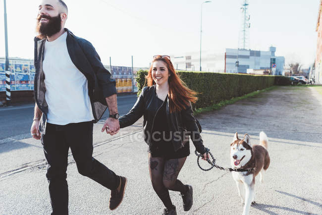 Junges Paar geht mit Hund draußen spazieren — Stockfoto