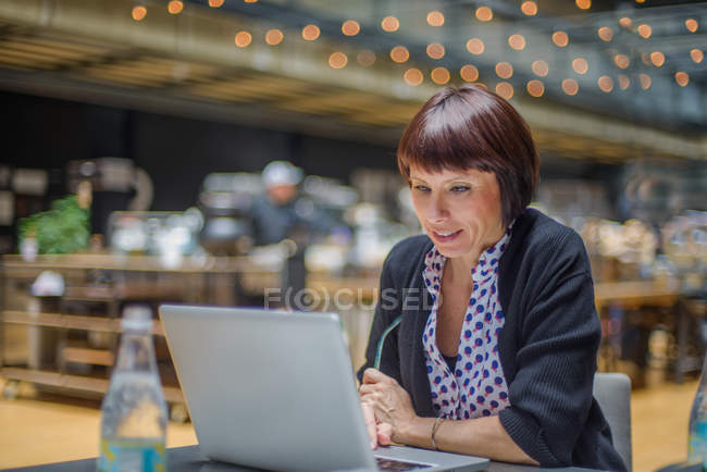 Зріла жінка використовує ноутбук в кафе — стокове фото