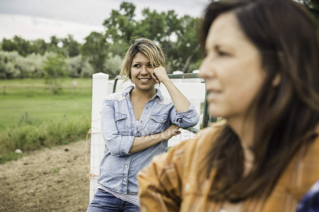 Дві жінки, що стоять на фермі, посміхаються — стокове фото