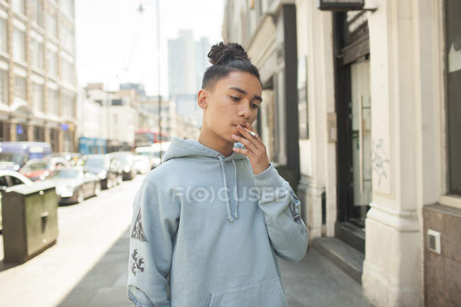 Portrait of Young man smoking cigarette on city street — Stock Photo