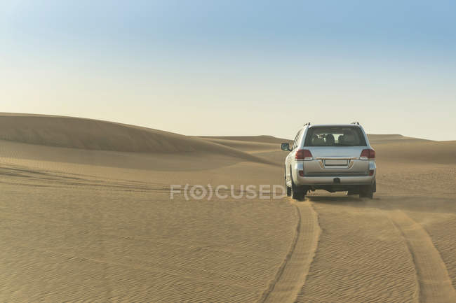 Auto a cavallo attraverso il deserto tra le colline di sabbia — Foto stock