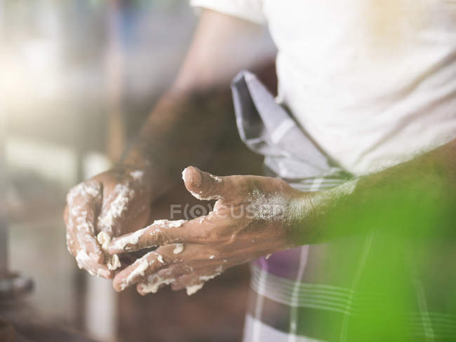 Man removing roti dough from fingers — Stock Photo