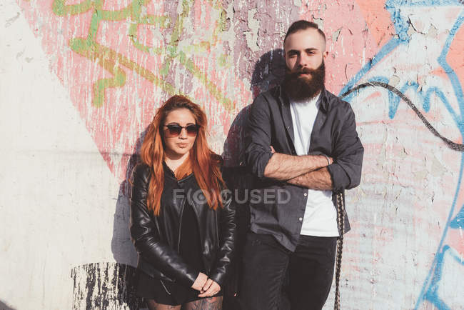 Jeune couple appuyé contre le mur de graffiti — Photo de stock