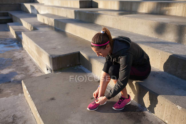 Mujer joven atando cordones en zapato de entrenamiento - foto de stock