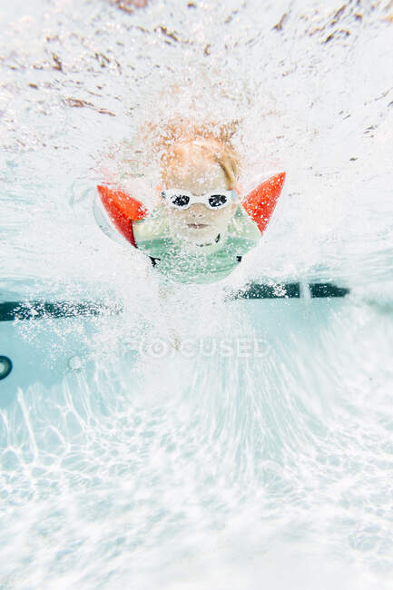Мальчик плавает под водой в бассейне, с видом на море — стоковое фото