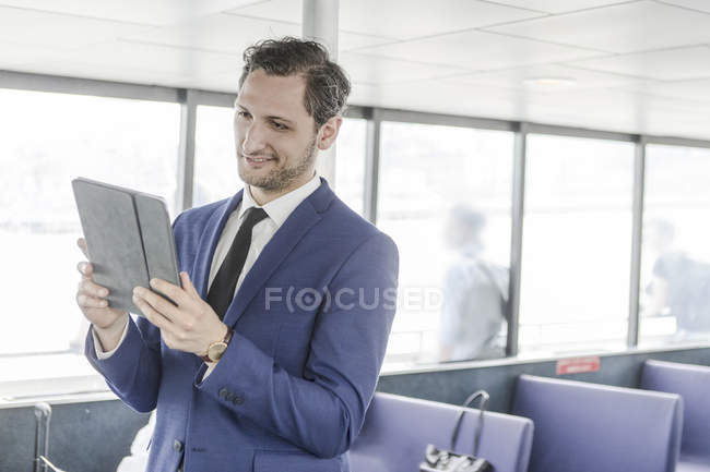 Jeune homme d'affaires regardant tablette numérique sur ferry à passagers — Photo de stock