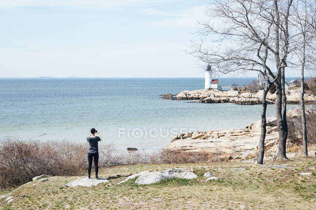 Rückansicht einer Frau, die auf einer Klippe steht und aufs Meer blickt, Annisquam Harbor, Gloucester, Massachusetts, Vereinigte Staaten, Nordamerika — Stockfoto