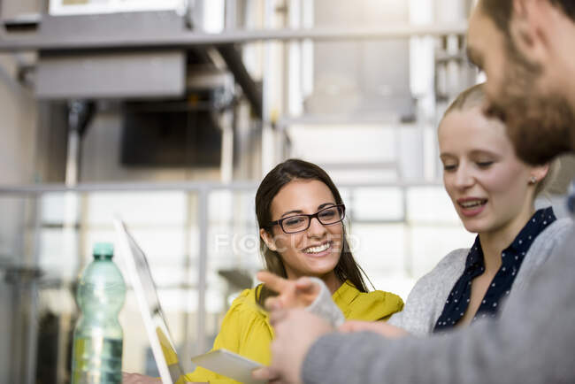 Male and female designers pointing at laptop on design studio desk — Stock Photo