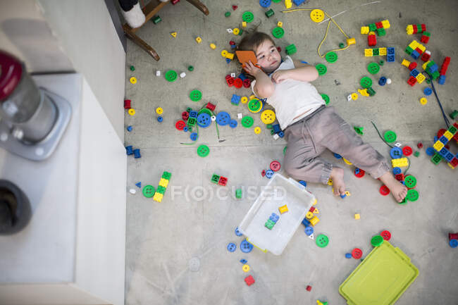 Bambina sdraiata sul retro utilizzando il telefono cellulare — Foto stock
