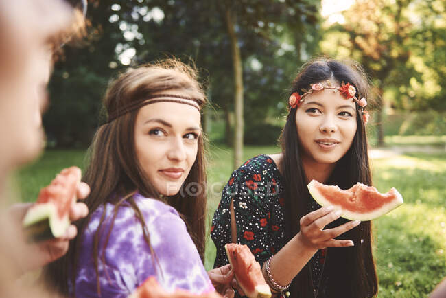 Jovens boho mulheres comendo fatia de melão no festival — Fotografia de Stock
