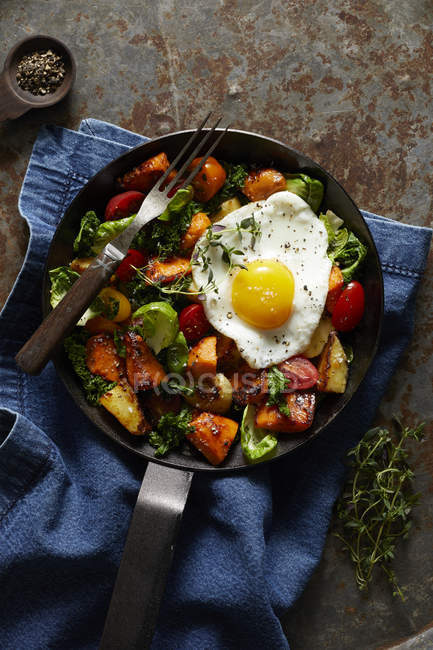 Breakfast hash with fried egg in cast iron skillet — Stock Photo