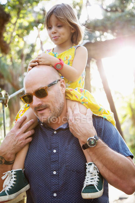 Vater und Tochter gehen ins Freie, Vater trägt Tochter auf Schultern — Stockfoto
