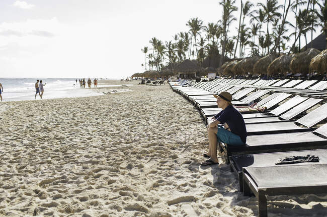 Ragazzo seduto sul lettino sulla spiaggia, guardando la vista — Foto stock