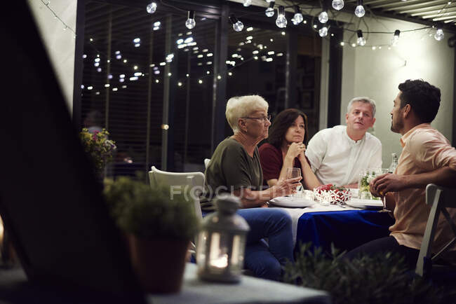 Grupo de pessoas sentadas à mesa, desfrutando de refeição — Fotografia de Stock