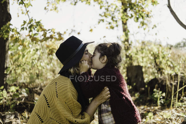 Madre besando y abrazando hija - foto de stock