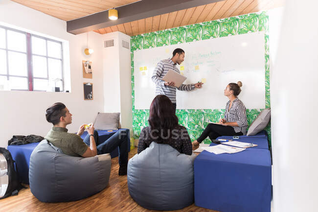 Homem de negócios americano africano apontando para quadro branco na sala de reuniões criativas — Fotografia de Stock
