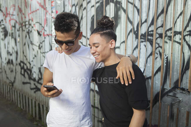 Dos jóvenes en la calle, mirando el teléfono inteligente - foto de stock