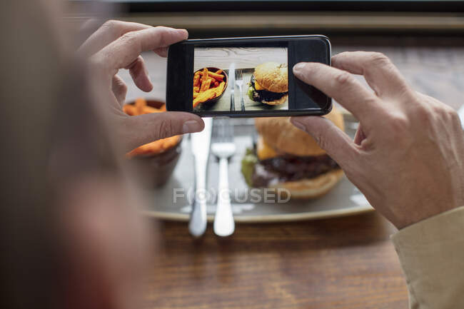Homme photographiant de la nourriture avec smartphone — Photo de stock