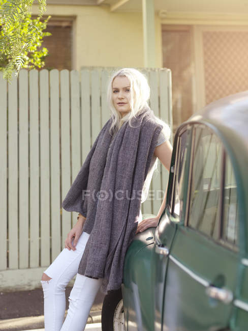 Young woman leaning against car — Stock Photo