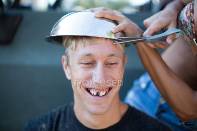 Donna che taglia i capelli del giovane usando ciotola, denti di uomo oscurati — Foto stock