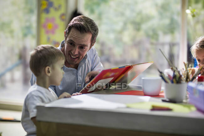Enseignant regardant livre avec enfant — Photo de stock