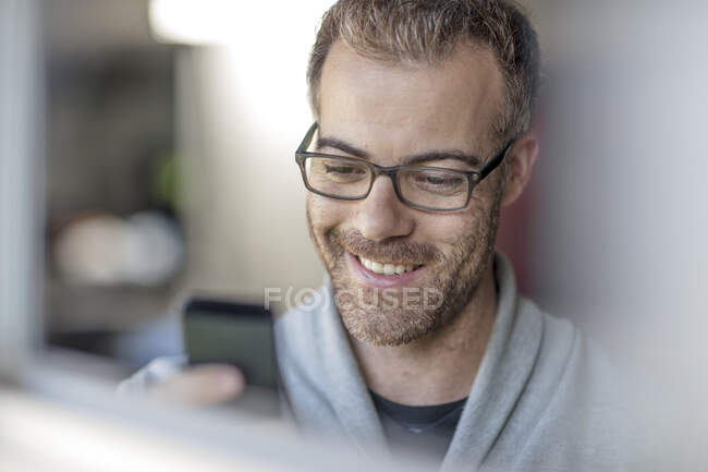 Happy businessman looking at smartphone at home — Stock Photo