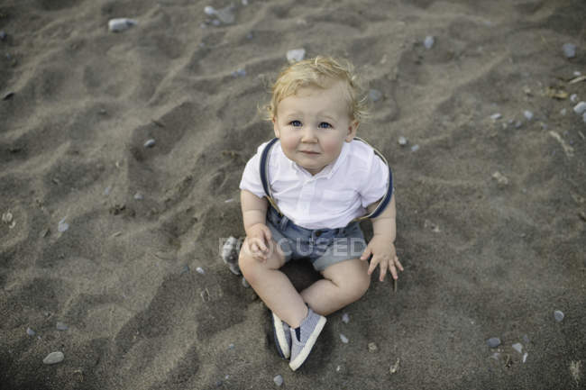Портрет мальчика, сидящего на песке — стоковое фото
