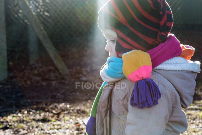 Bambino maschio in maglia cappello e sciarpa guardando giù nel parco — Foto stock