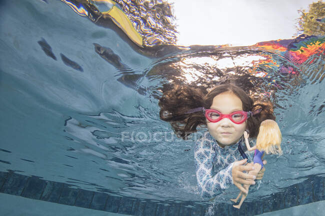 Retrato subaquático de menina nadando segurando boneca — Fotografia de Stock