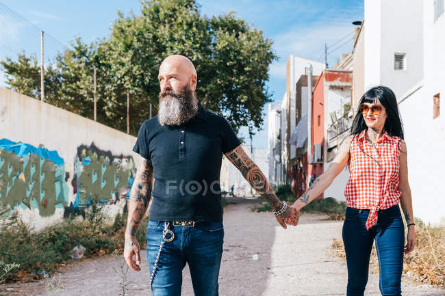 Mature hipster couple strolling down alleyway — Stock Photo