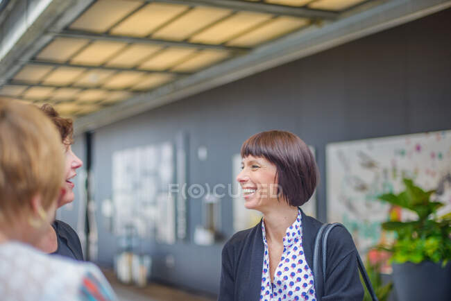 Woman in office chatting with colleagues smiling — Stock Photo