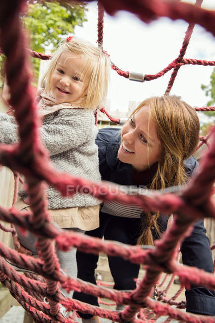 Mãe e filha criança no parque infantil escalada quadro — Fotografia de Stock