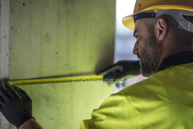 Travailleur de la construction mesurant bâtiment — Photo de stock