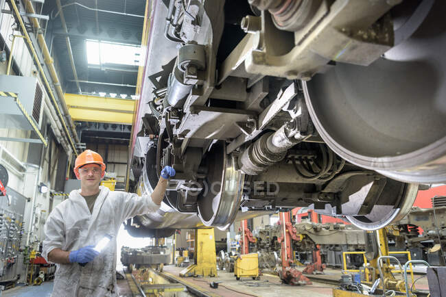 Apprentice locomotive engineer working on locomotive in train works — Stock Photo