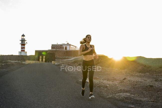 Jeune coureuse sur route rurale au coucher du soleil, Las Palmas, Îles Canaries, Espagne — Photo de stock