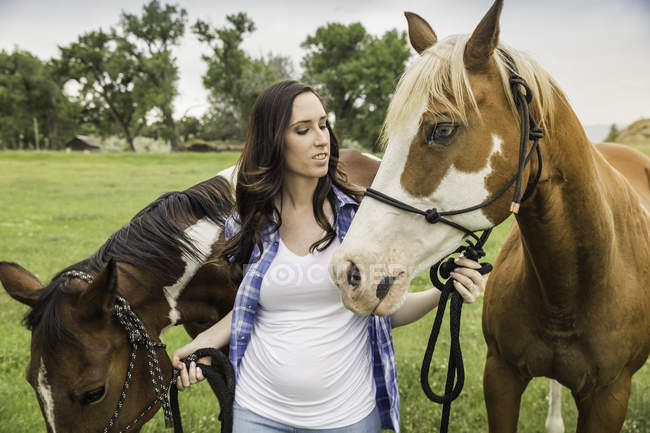 Junge Frau führt zwei Pferde in Ranch Feld, Bridger, Montana, USA — Stockfoto