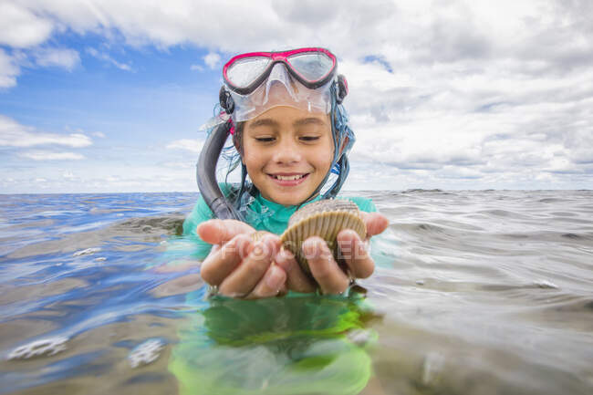 Девушка держит свежие пойманные гребешки — стоковое фото