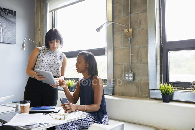 Femme adulte moyenne montrant l'écran de la tablette numérique à un collègue — Photo de stock