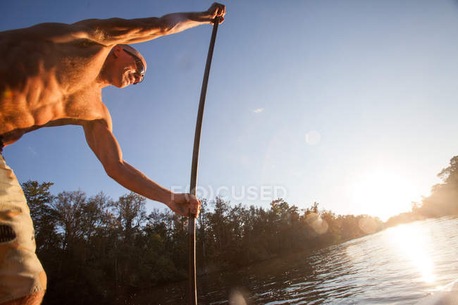 Vue à faible angle de l'homme mature en utilisant la pagaie sur l'eau — Photo de stock