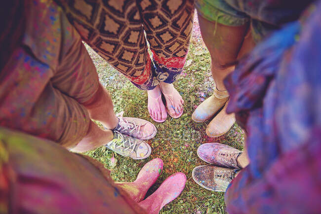 Overhead view of young adults in circle covered in coloured chalk powder at festival — Stock Photo