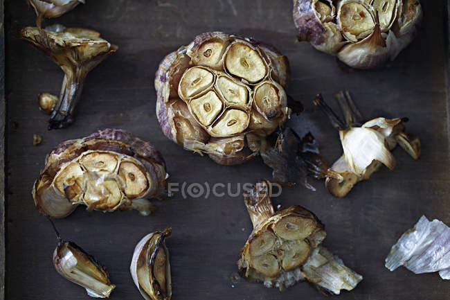 Вид сверху на жареные луковицы чеснока на столе, крупным планом — стоковое фото