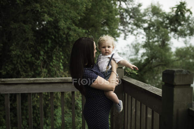 Pregnant woman carrying toddler son on balcony — Stock Photo