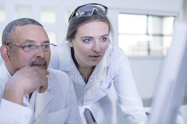 Dois trabalhadores de laboratório olhando para a tela do computador — Fotografia de Stock