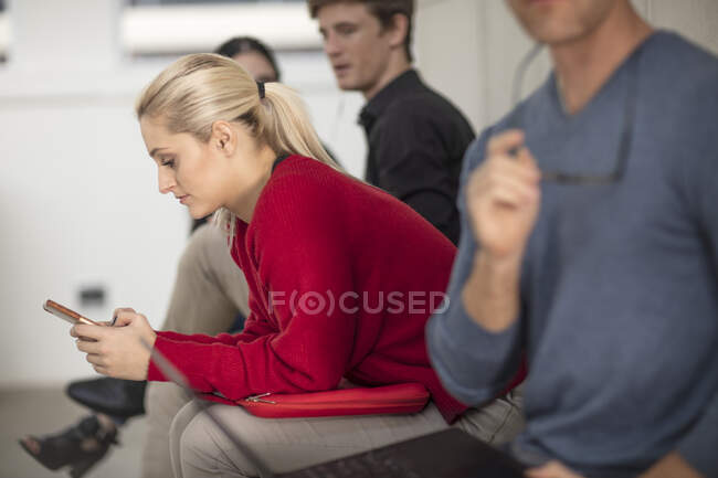 Uomini e donne impiegati in cerca di laptop e smartphone in riunione — Foto stock