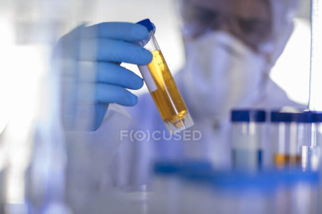Travailleur de laboratoire tenant une éprouvette remplie de liquide, gros plan — Photo de stock