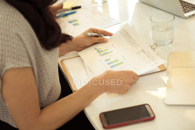 Businesswoman looking at bar charts at desk — Stock Photo