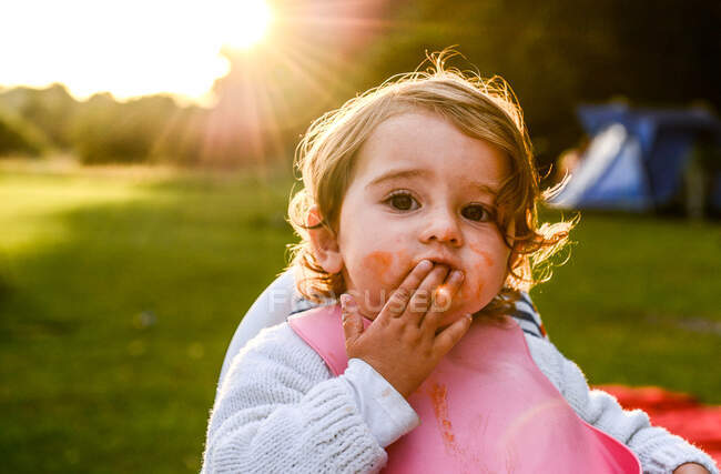 Portrait d'une petite fille qui mange le petit déjeuner avec les doigts sur le camping — Photo de stock