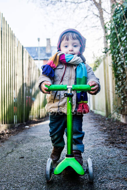 Portrait of male toddler on push scooter in lane — Stock Photo