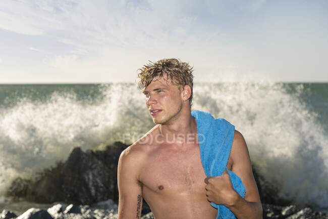 Young male swimmer on beach with splashing waves — Stock Photo